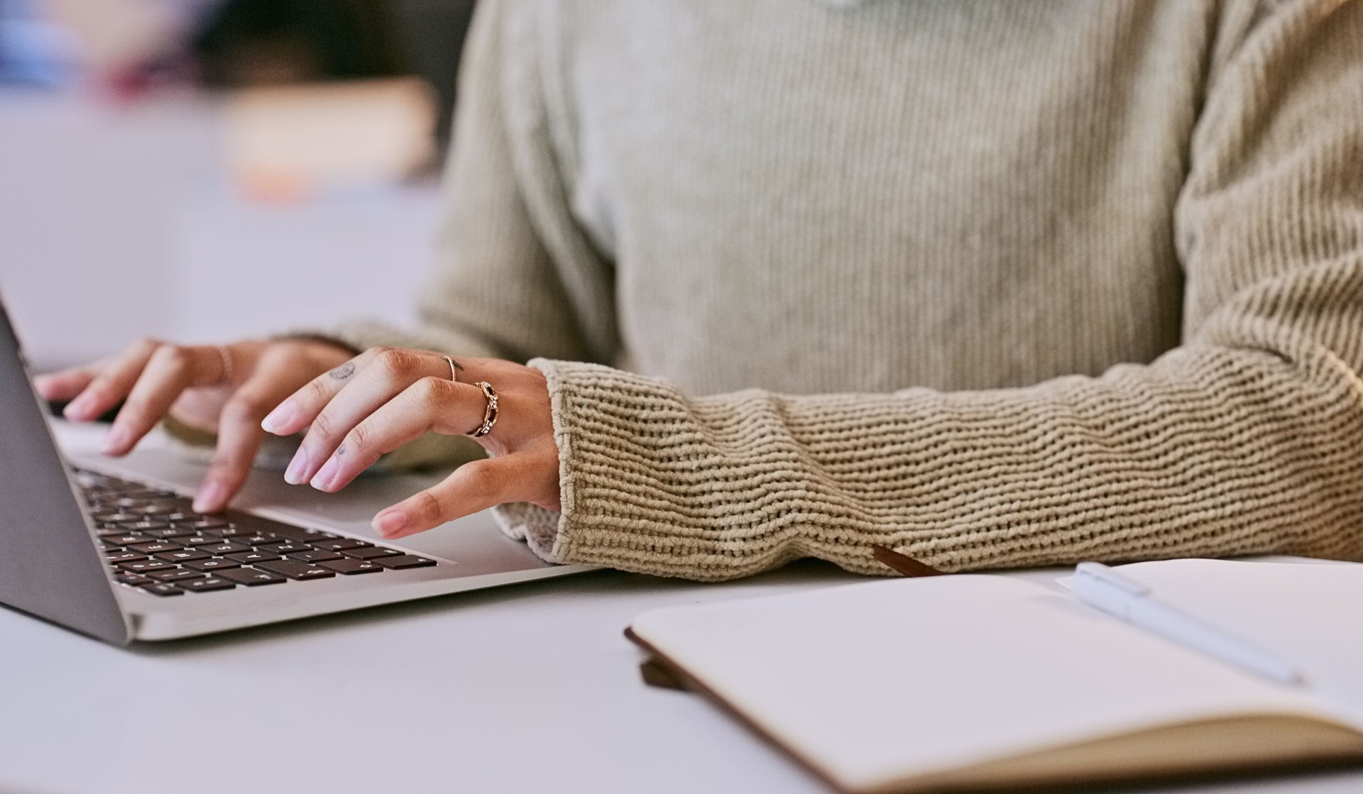 Person, hands and laptop typing or notebook for student education or university project proposal, research or brainstorming. Scholar, fingers and online at college or elearning, connection or article